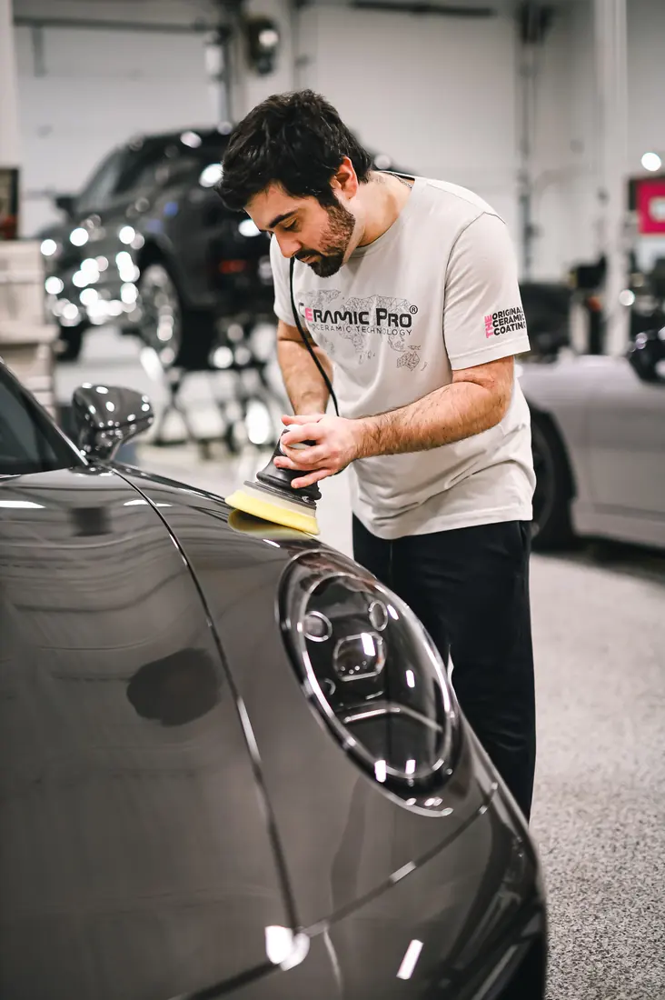 Polish para auto: Técnico puliendo el cofre de un auto con pulidora orbital y pad verde