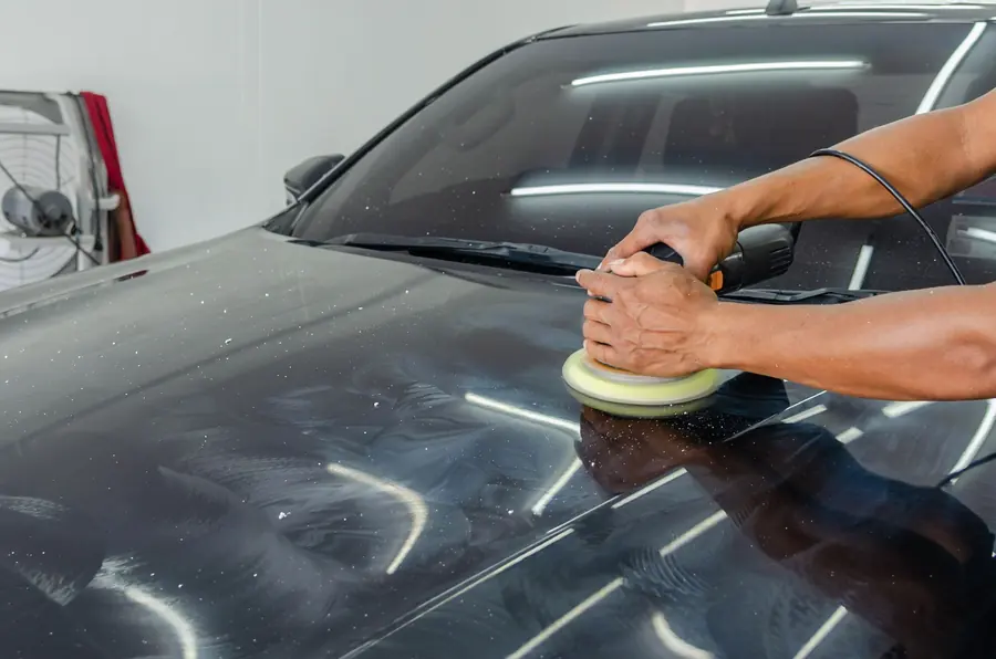 Pulir auto a mano: Sellador en atomizador y toalla de microfibra sobre pintura negra